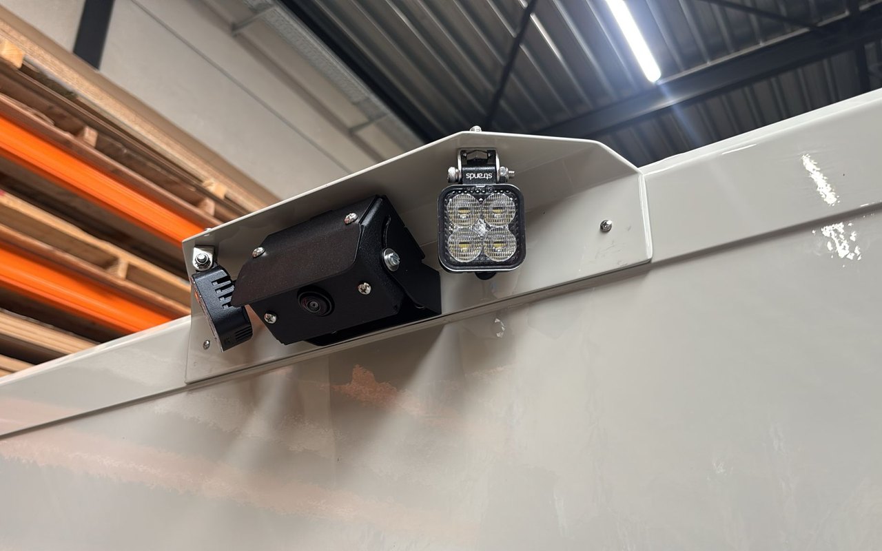 De camerasteun met achteruitrijcamera en LED-werklamp gemonteerd op een bedrijfsvoertuig